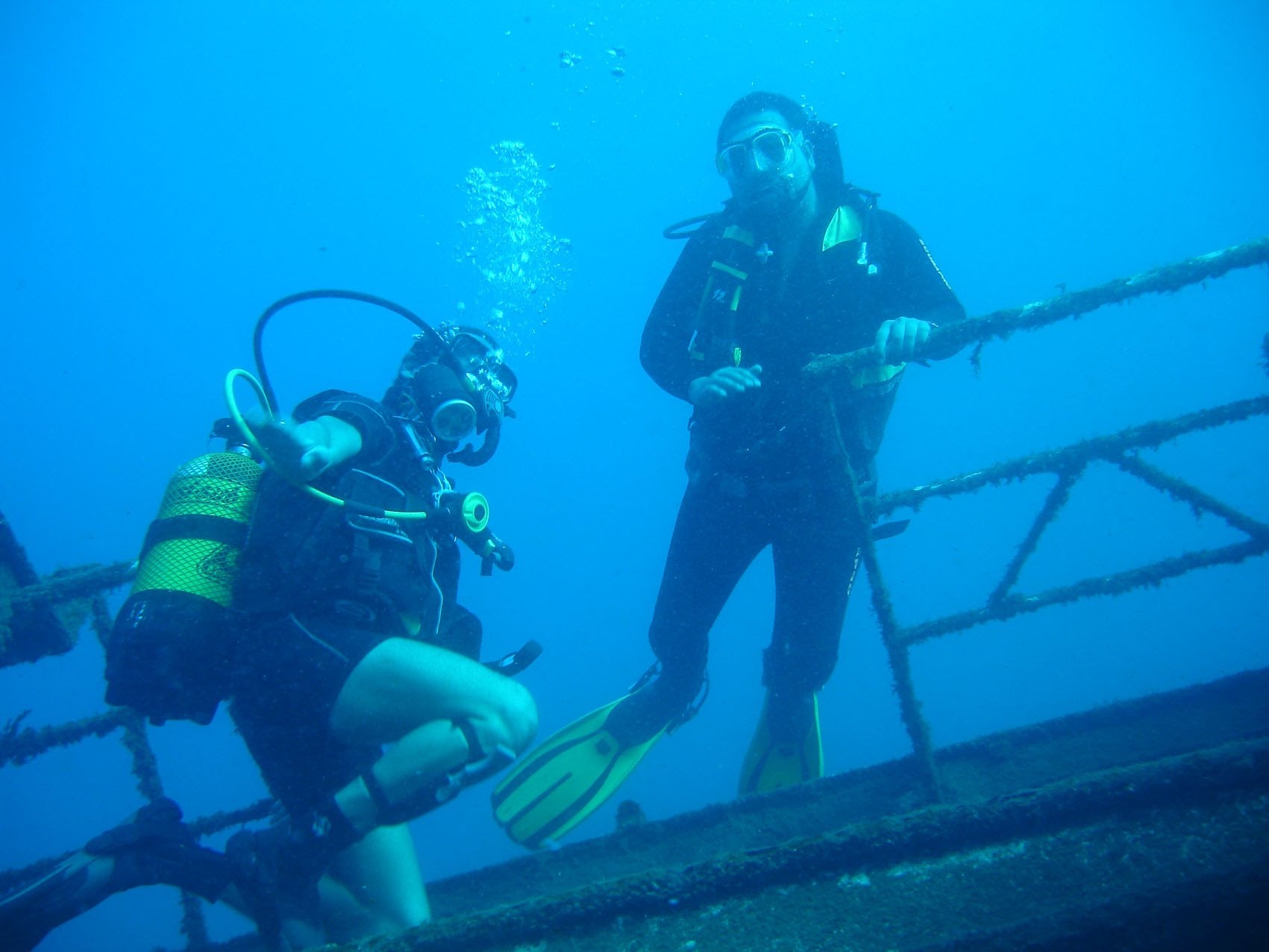 Dos buceadores explorando la estructura de un barco hundido