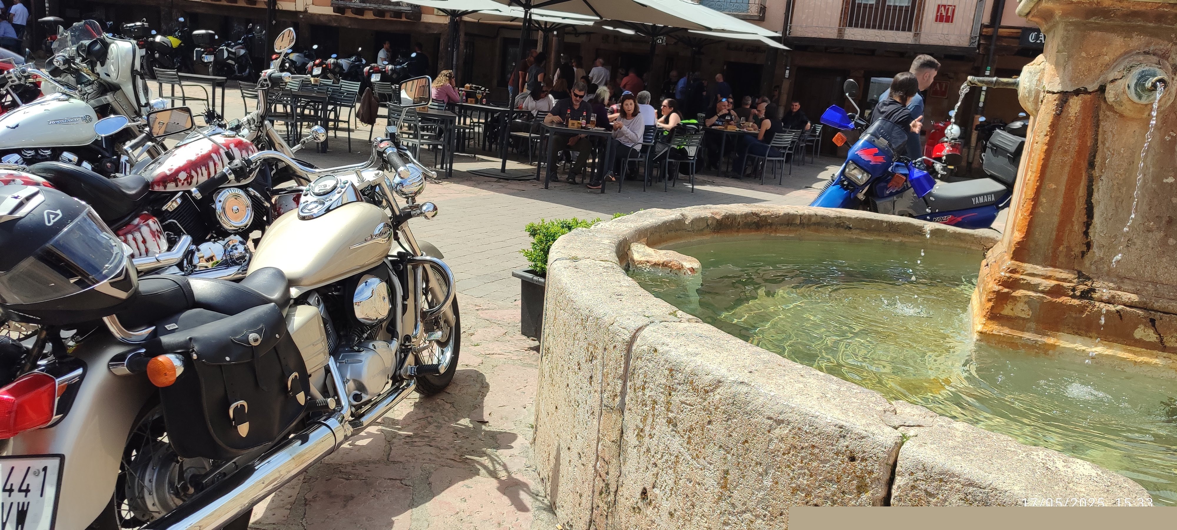 Motos custom aparcadas junto a fuente de piedra en plaza